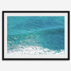 Aerial beach wall art featuring a lone surfer paddling through turquoise ocean waves, with foamy white surf along the shoreline.