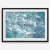 Fine art aerial photography print of a lone surfer floating on a surfboard amidst turquoise ocean waves with intricate white foam patterns.