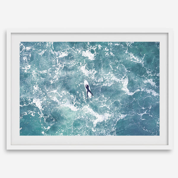 Fine art aerial photography print of a lone surfer floating on a surfboard amidst turquoise ocean waves with intricate white foam patterns.