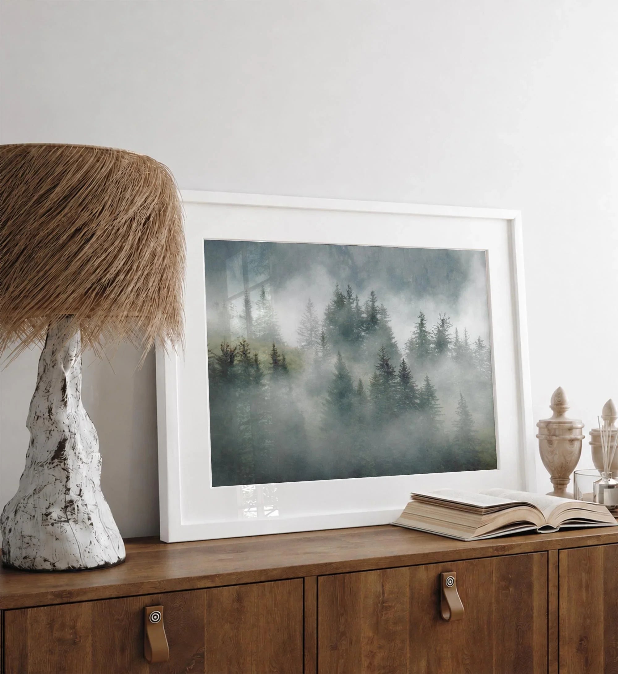 Fine art photography of a misty forest in Alaska, with the tops of trees on a mountain shrouded in white dreamlike fog.