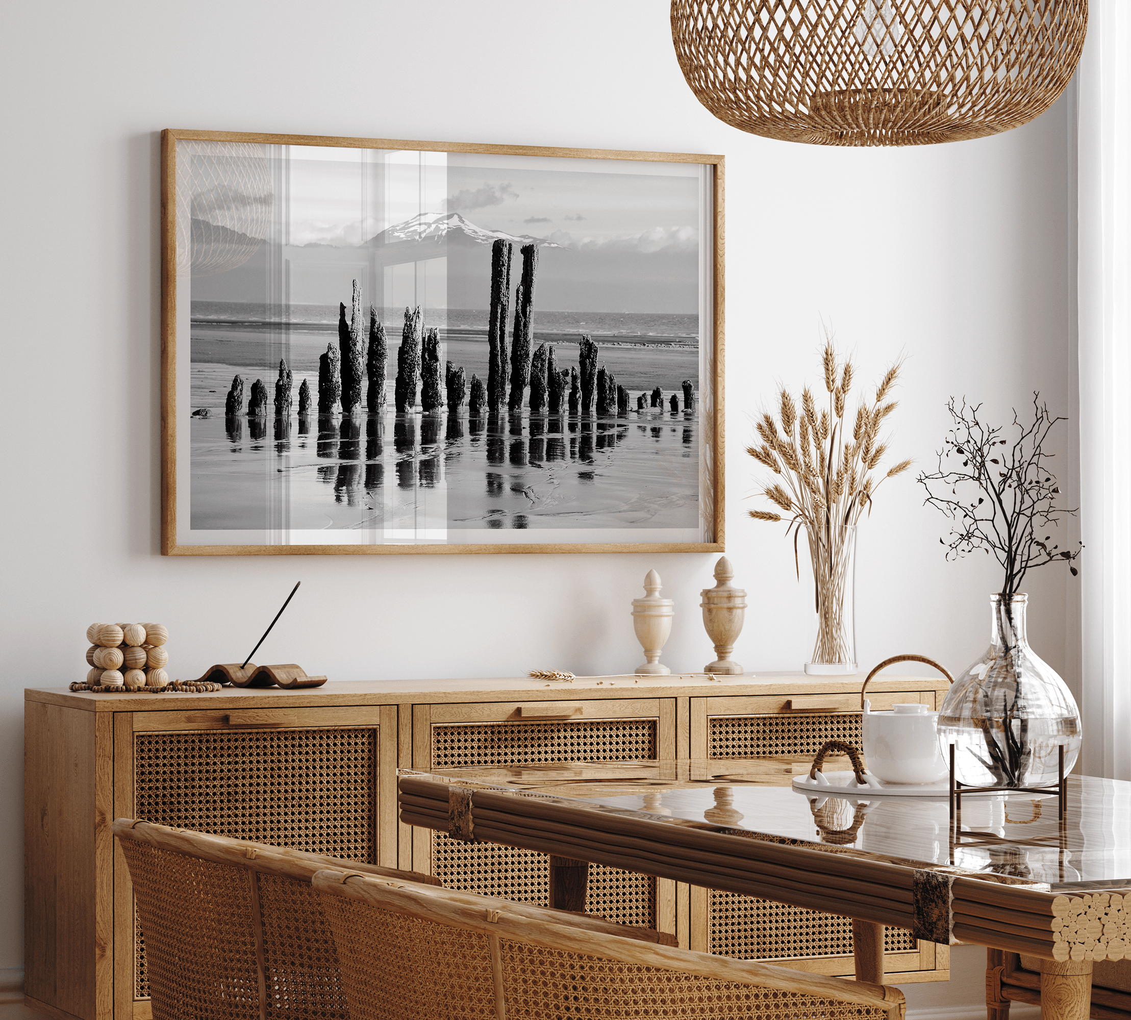 Black and white photo of weathered pilings on an Alaskan beach with snow-capped mountains in the background – fine art print.