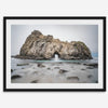 Fine art print showcasing a magnificent rock formation framing the horizon and crashing waves, with scattered rocks adding texture. Captivating and soothing, this print is a timeless addition to any space, evoking relaxation and awe-inspiring beauty.
