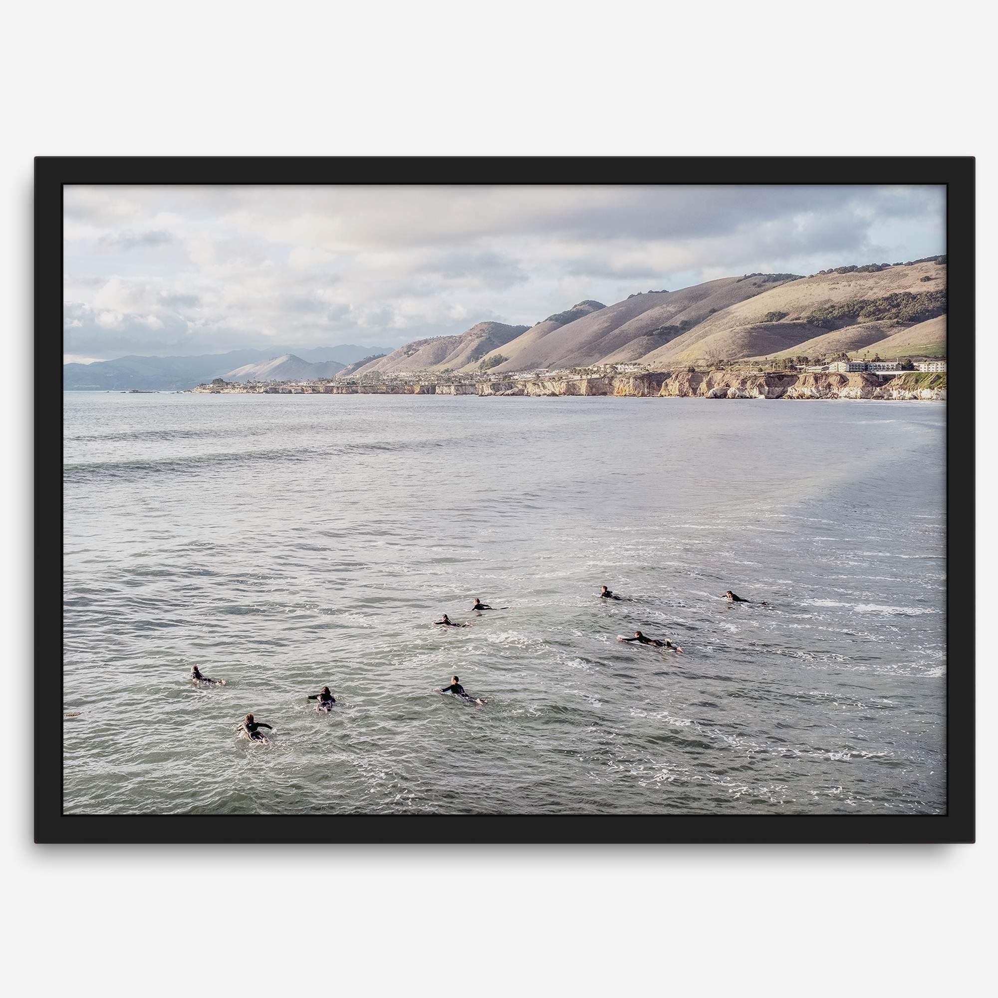 Surfers paddling near Pismo Beach captured in a fine art photography print with coastal cliffs and serene ocean views.