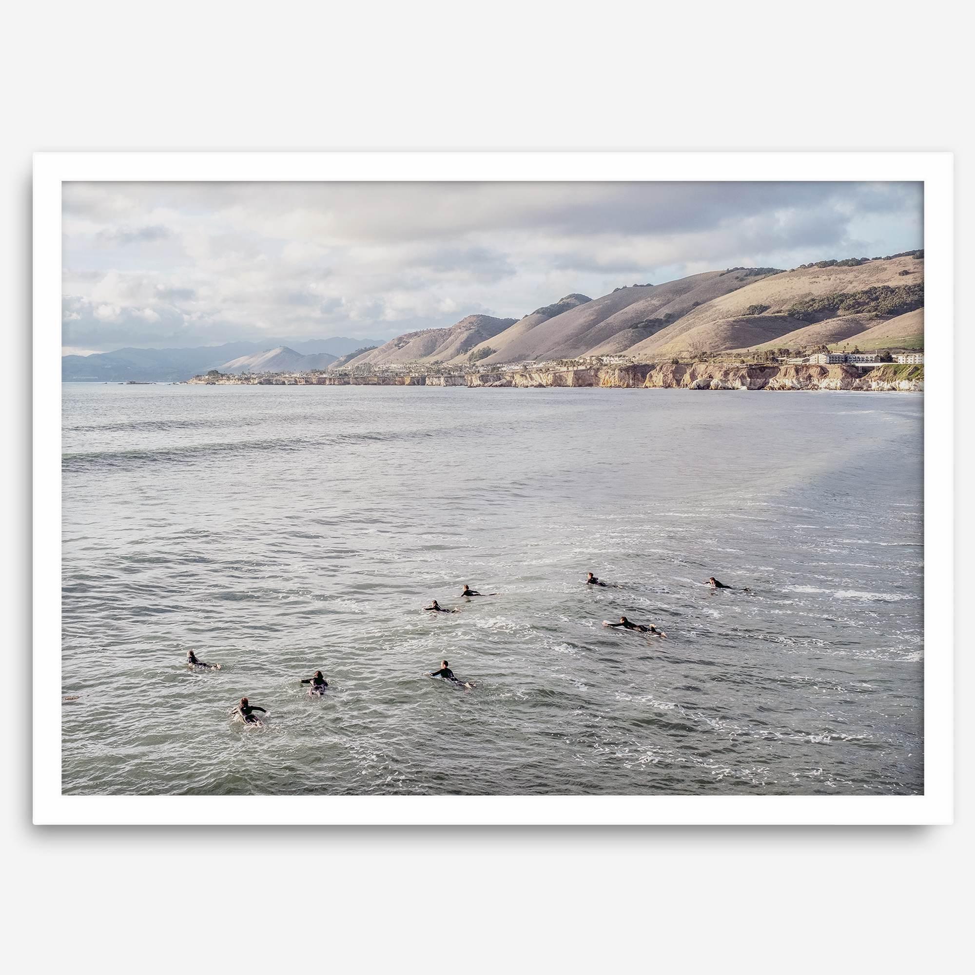 Surfers paddling near Pismo Beach captured in a fine art photography print with coastal cliffs and serene ocean views.