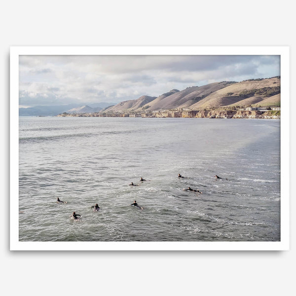 Surfers paddling near Pismo Beach captured in a fine art photography print with coastal cliffs and serene ocean views.