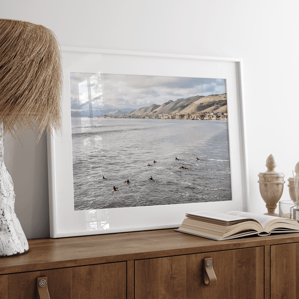 Surfers paddling near Pismo Beach captured in a fine art photography print with coastal cliffs and serene ocean views.