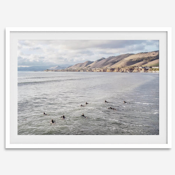 Surfers paddling near Pismo Beach captured in a fine art photography print with coastal cliffs and serene ocean views.
