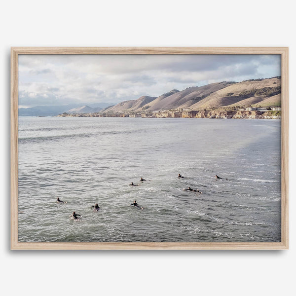 Surfers paddling near Pismo Beach captured in a fine art photography print with coastal cliffs and serene ocean views.