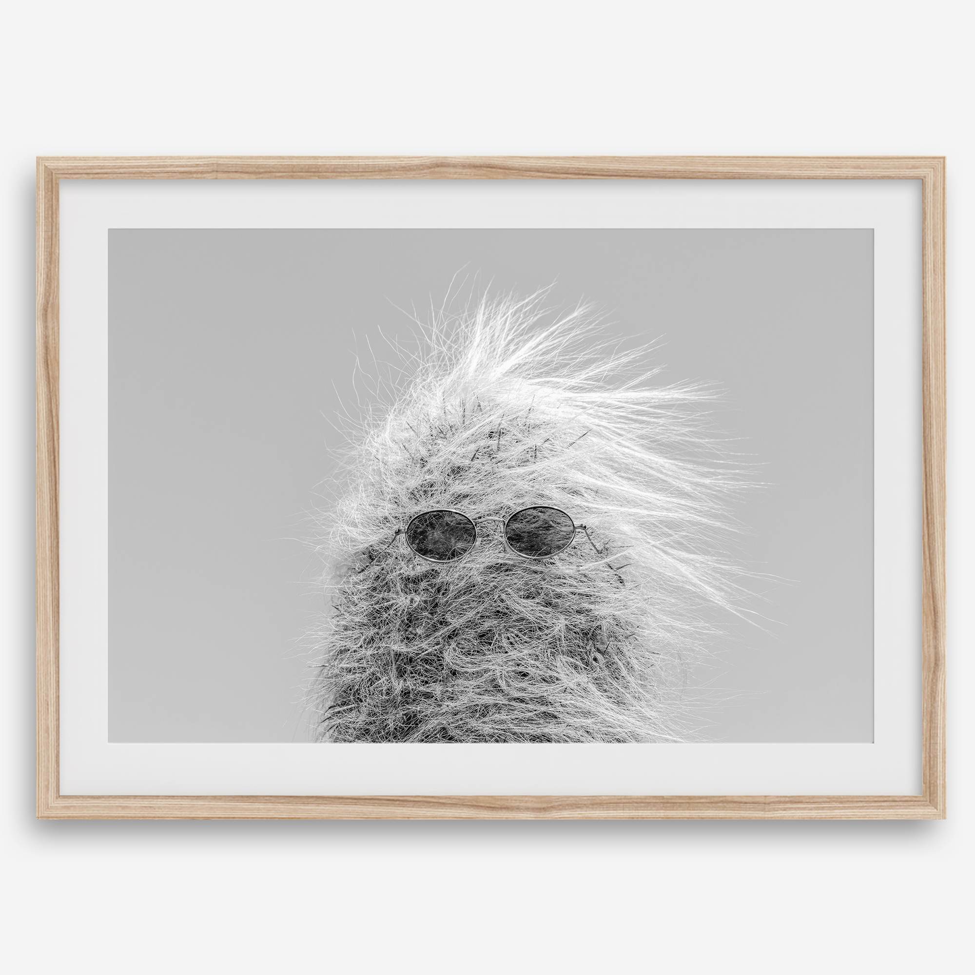Black-and-white cactus print featuring a windswept cool cactus with sunglasses in a minimalist desert setting.