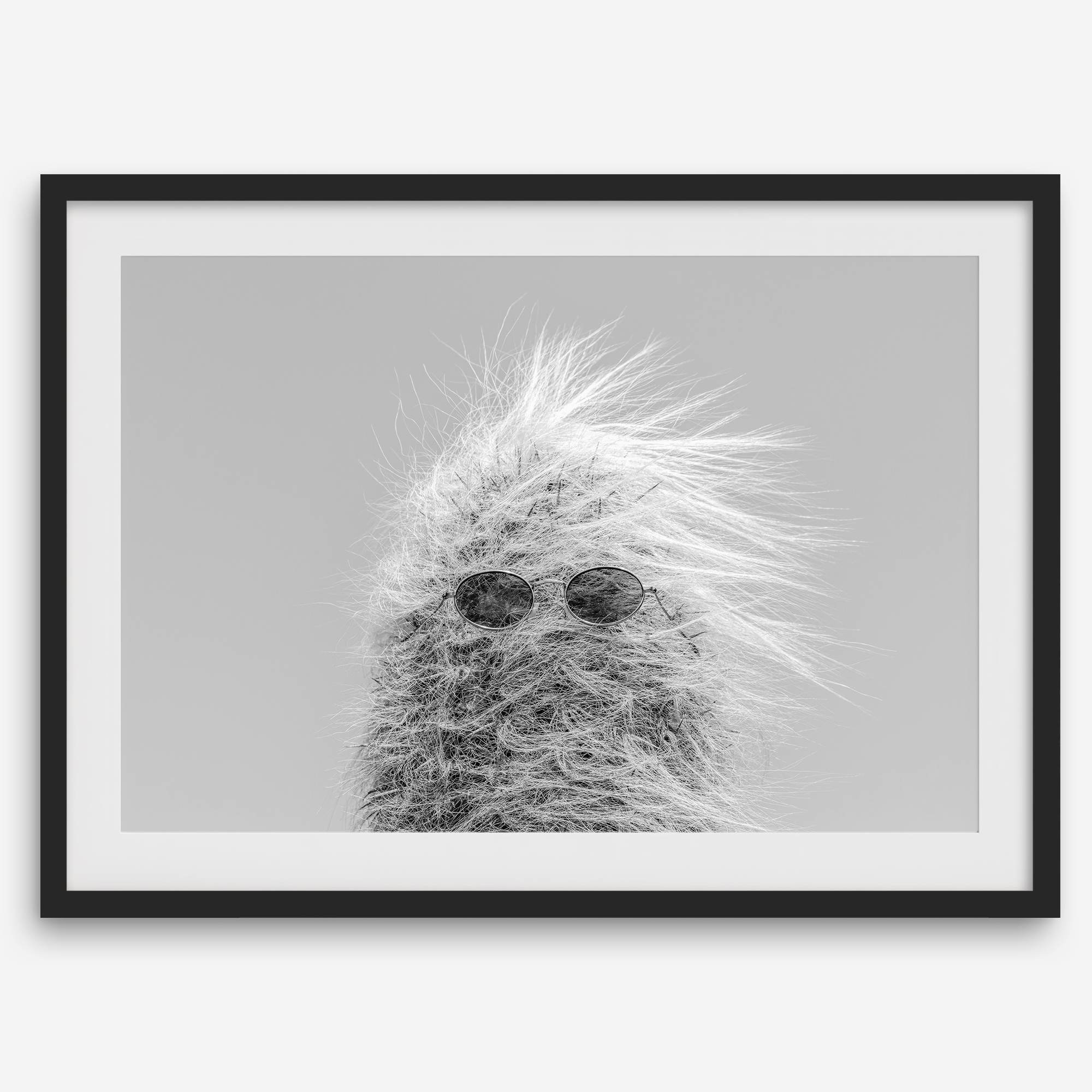 Black-and-white cactus print featuring a windswept cool cactus with sunglasses in a minimalist desert setting.