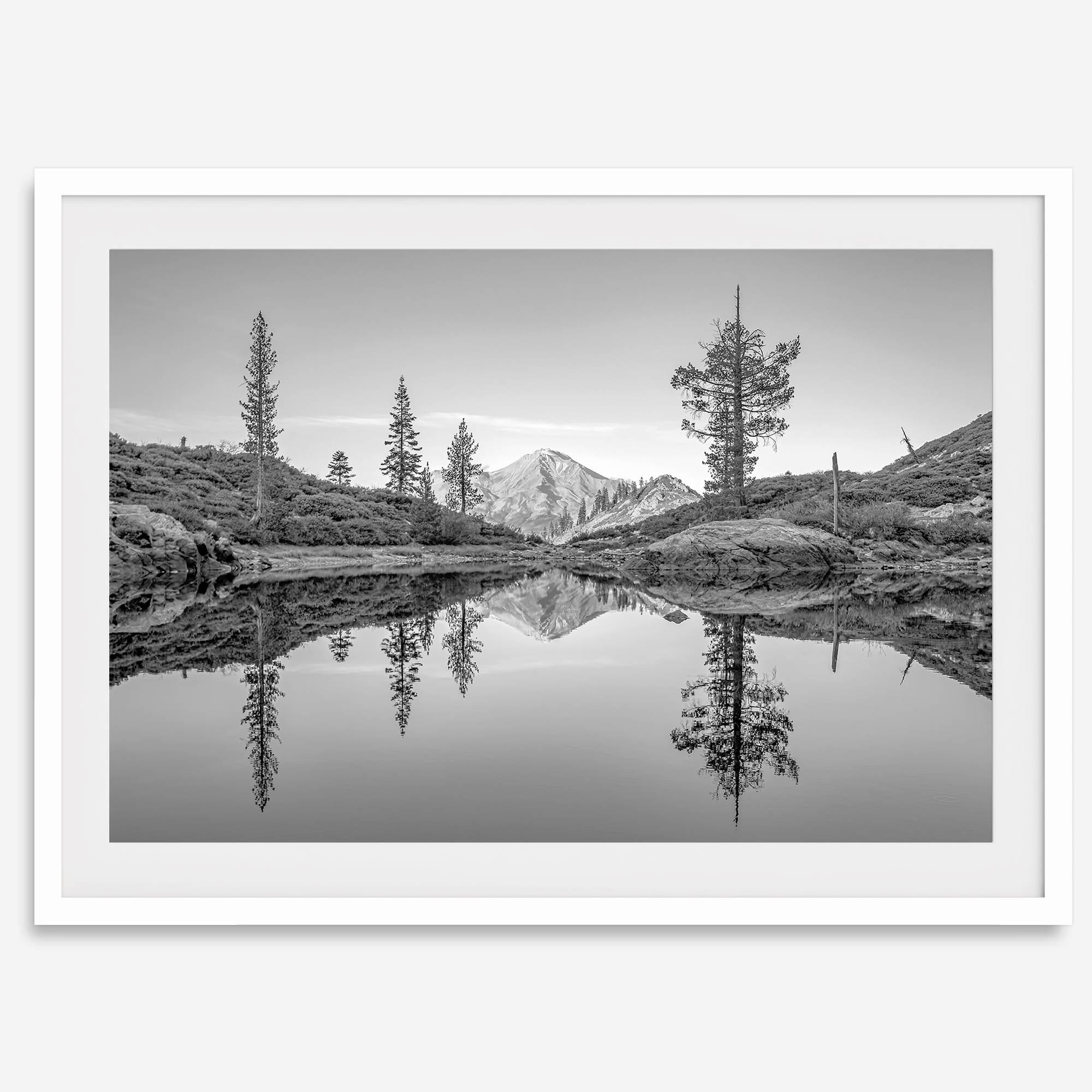 Black and white fine art photo of a serene mountain and forest mirrored in a still lake at sunset.