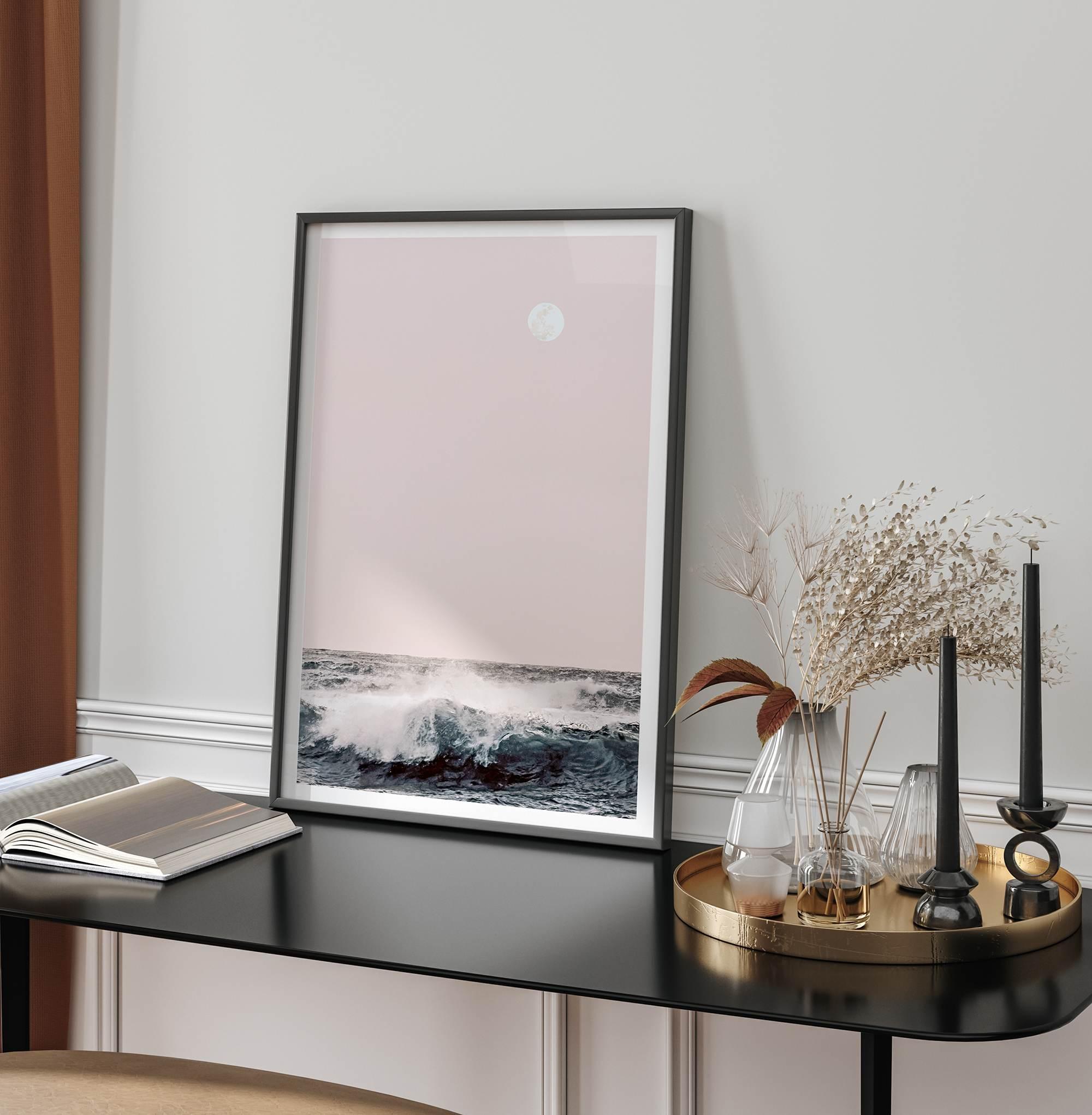 This extraordinary ocean wall art captures a mesmerizing moment when a powerful wave crashes while the sunset gentle blush pink hues fill the sky and a large full moon rises majestically in the backdrop.