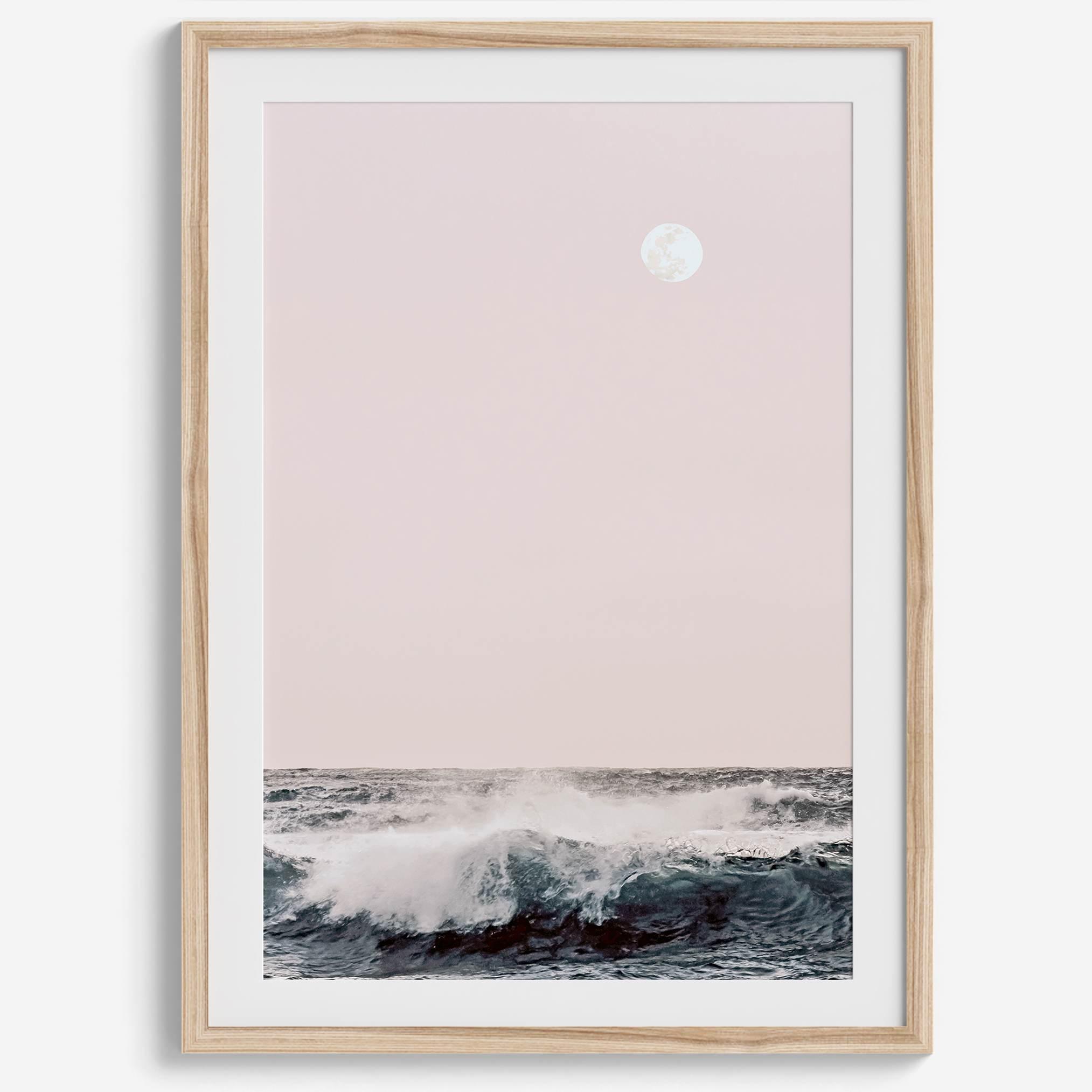 This extraordinary ocean wall art captures a mesmerizing moment when a powerful wave crashes while the sunset gentle blush pink hues fill the sky and a large full moon rises majestically in the backdrop.