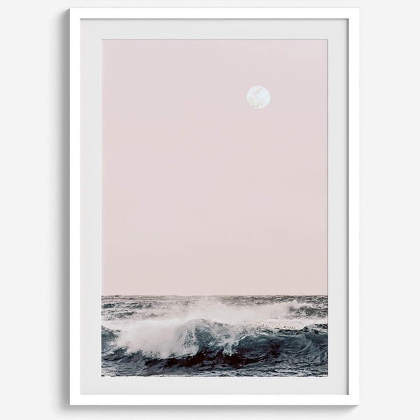 This extraordinary ocean wall art captures a mesmerizing moment when a powerful wave crashes while the sunset gentle blush pink hues fill the sky and a large full moon rises majestically in the backdrop.