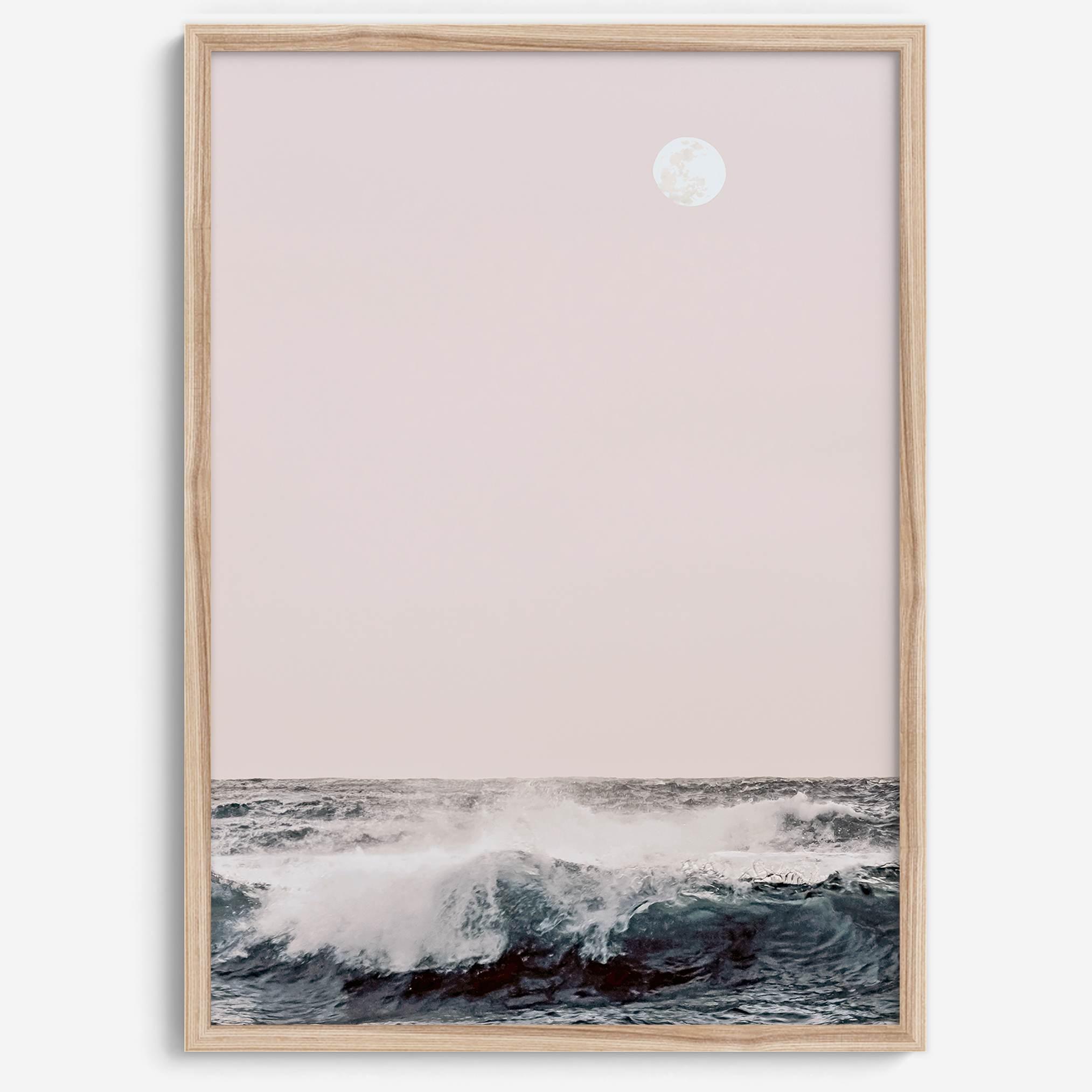 This extraordinary ocean wall art captures a mesmerizing moment when a powerful wave crashes while the sunset gentle blush pink hues fill the sky and a large full moon rises majestically in the backdrop.