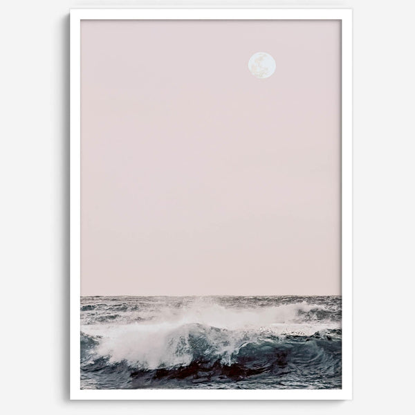 This extraordinary ocean wall art captures a mesmerizing moment when a powerful wave crashes while the sunset gentle blush pink hues fill the sky and a large full moon rises majestically in the backdrop.