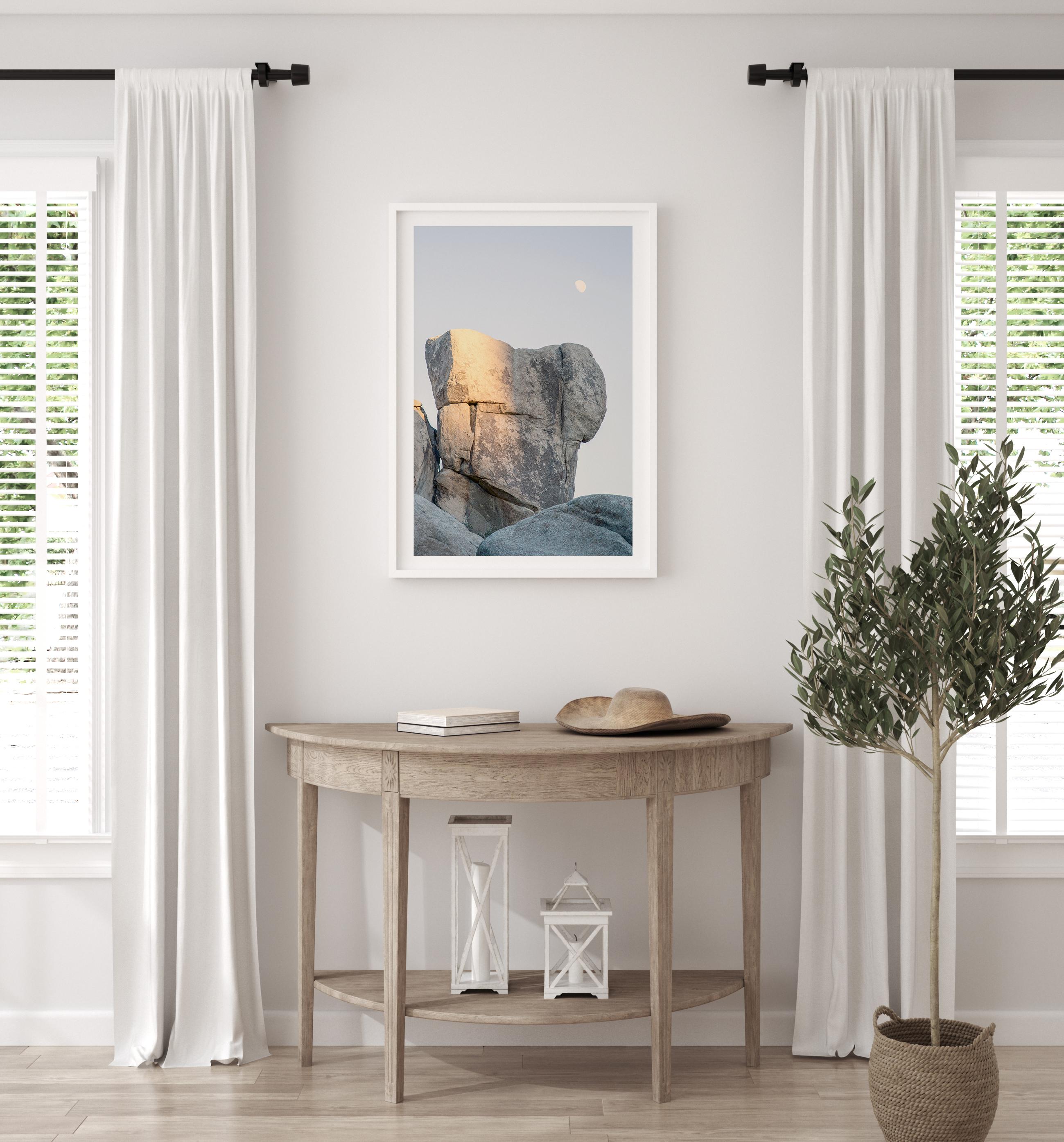 Minimalist desert moon wall art featuring massive sunlit rock formations beneath a pale moon and soft gray sky. Southwest fine art photography.
