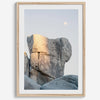 Minimalist desert moon wall art featuring massive sunlit rock formations beneath a pale moon and soft gray sky. Southwest fine art photography.