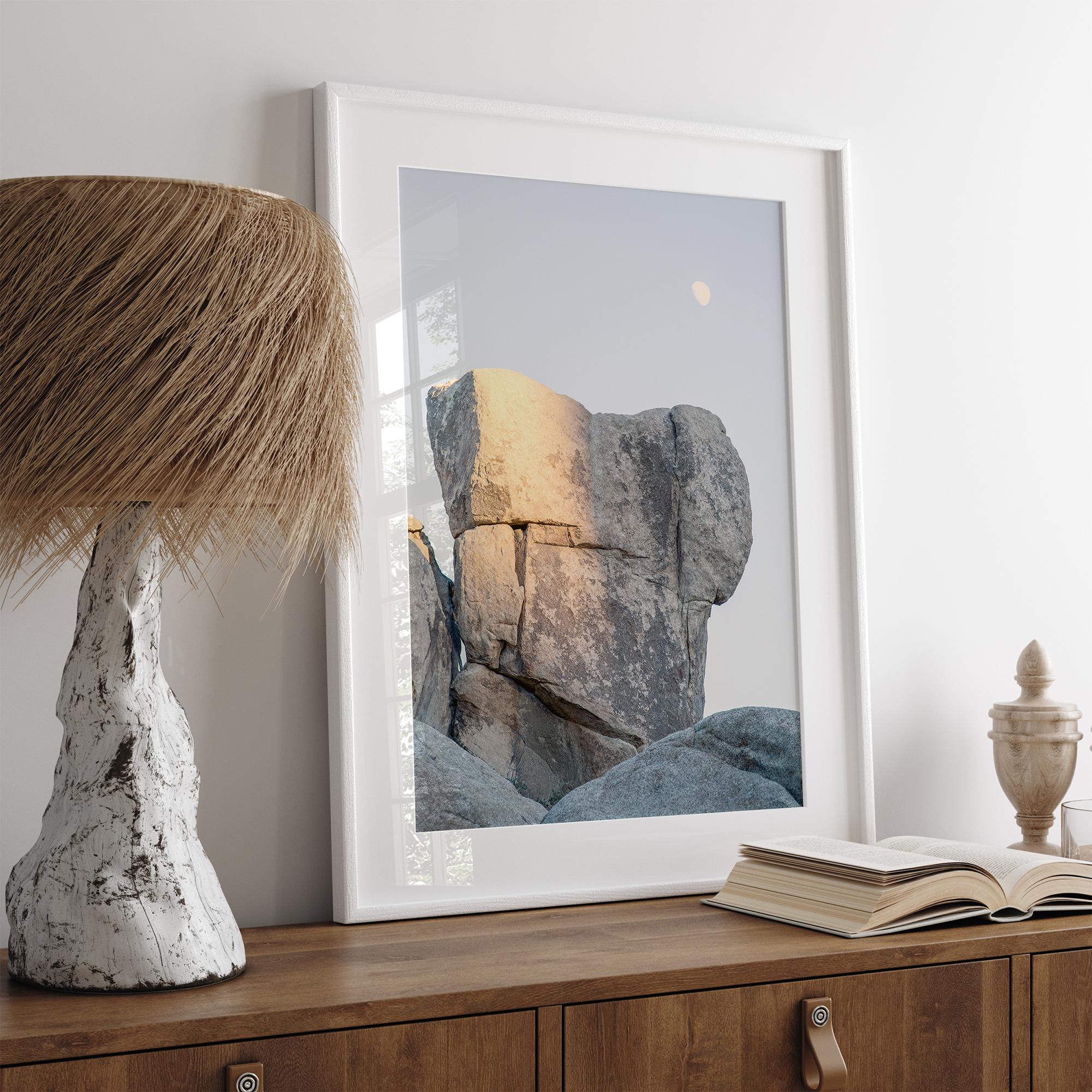 Minimalist desert moon wall art featuring massive sunlit rock formations beneath a pale moon and soft gray sky. Southwest fine art photography.