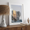 Minimalist desert moon wall art featuring massive sunlit rock formations beneath a pale moon and soft gray sky. Southwest fine art photography.