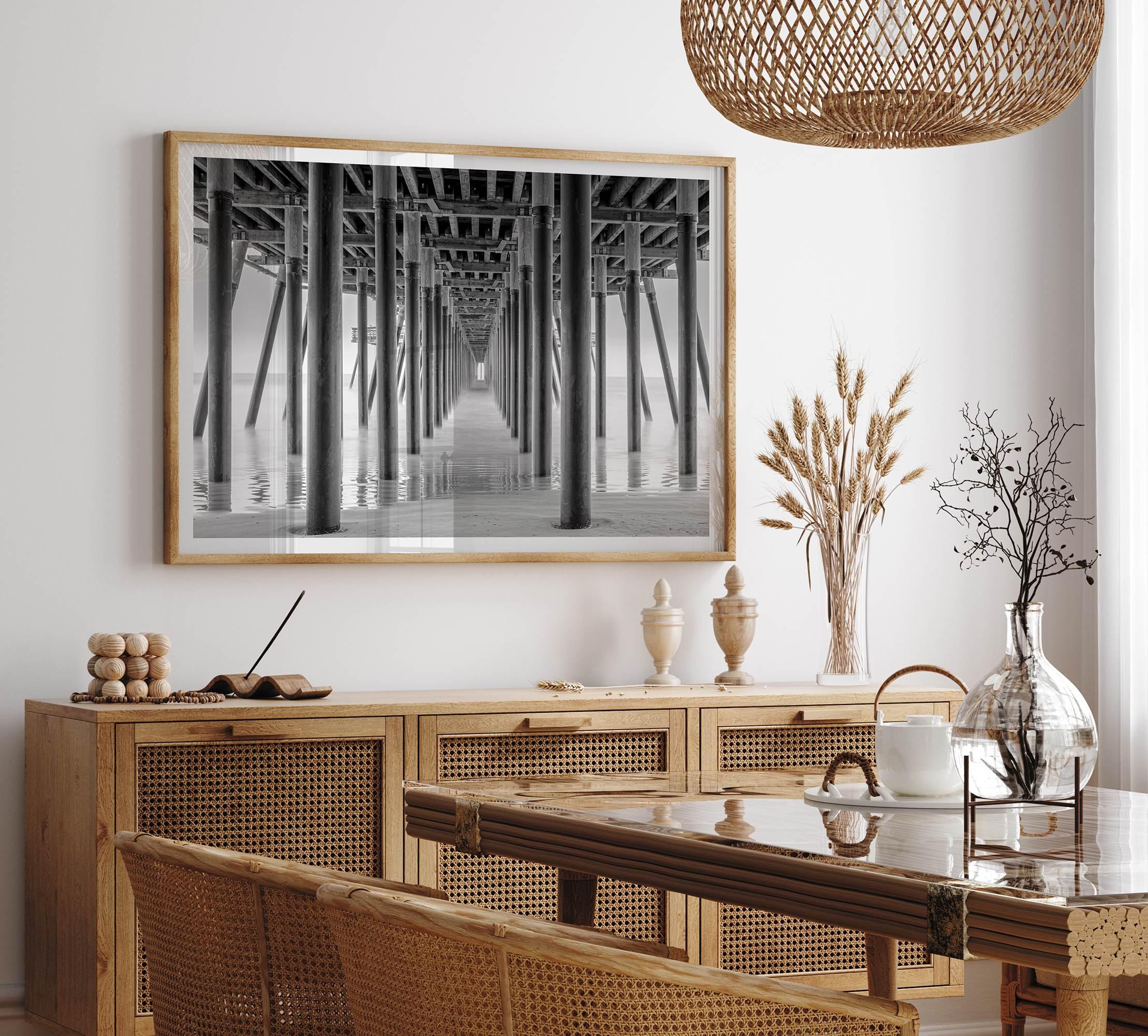 A large fine art abstract black and white beach pier print This stunning beach wall art shows the symmetric structure of the pier with the ocean water gently caressing the pier and beach.