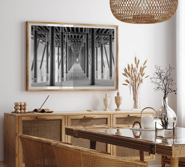 A large fine art abstract black and white beach pier print This stunning beach wall art shows the symmetric structure of the pier with the ocean water gently caressing the pier and beach.