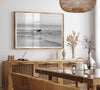 A fine art photography print capturing a female surfer walking back from the ocean at sunset with waves breaking in the foreground, capturing the end of a surf session.