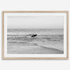 A fine art photography print capturing a female surfer walking back from the ocean at sunset with waves breaking in the foreground, capturing the end of a surf session.