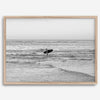 A fine art photography print capturing a female surfer walking back from the ocean at sunset with waves breaking in the foreground, capturing the end of a surf session.