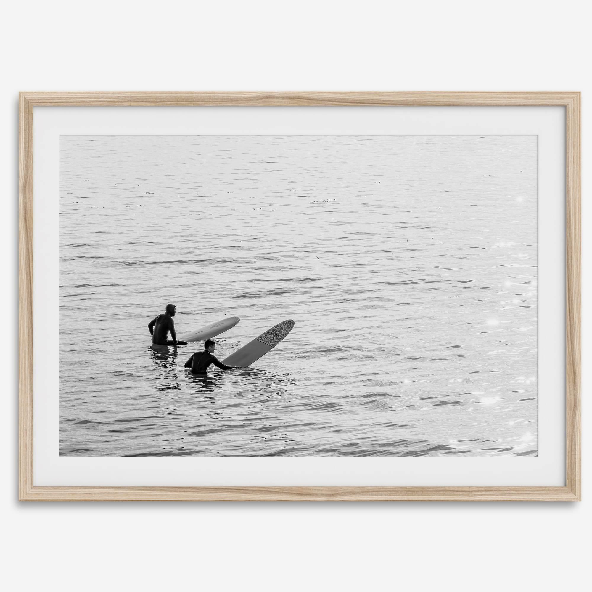 Black and white photo of two surfers with longboards waiting in calm ocean water – fine art surf photography print
