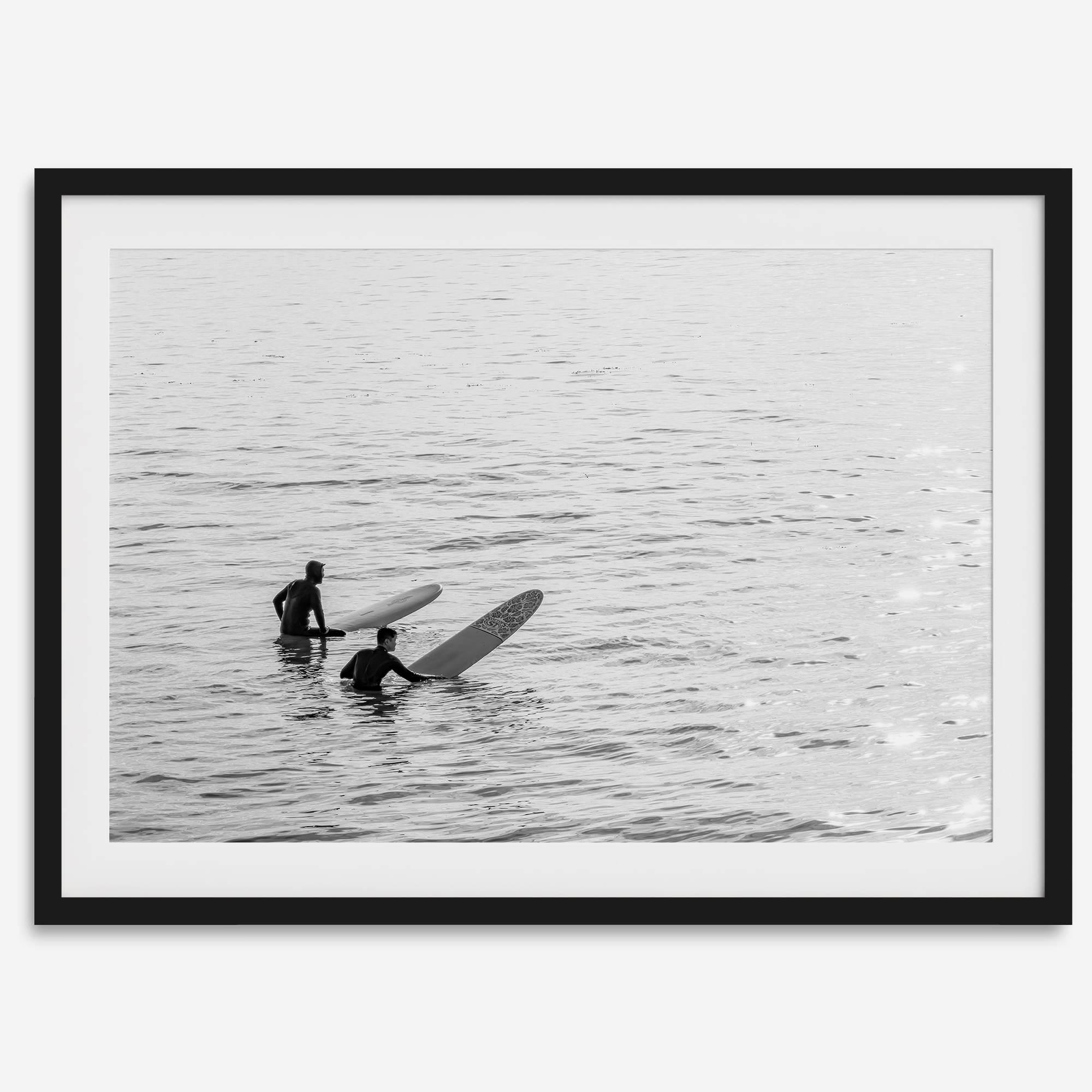 Black and white photo of two surfers with longboards waiting in calm ocean water – fine art surf photography print