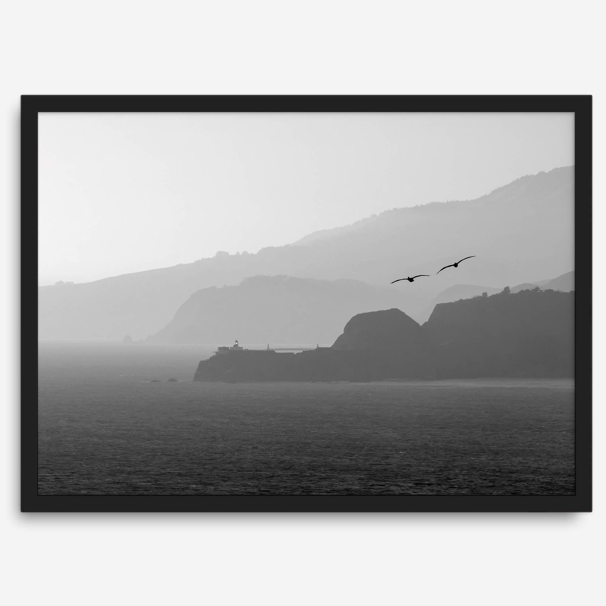 A black and white coastal wall art that showcases two Pelicans flying over the Pacific Ocean near the Golden Gate Bridge toward the layered mountains in the sunset.