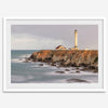 Long exposure fine art photography print of Pigeon Point Lighthouse at sunset. Golden light illuminates the lighthouse and cliffs, while the ocean surf crashes against the rocks in a creamy blur.