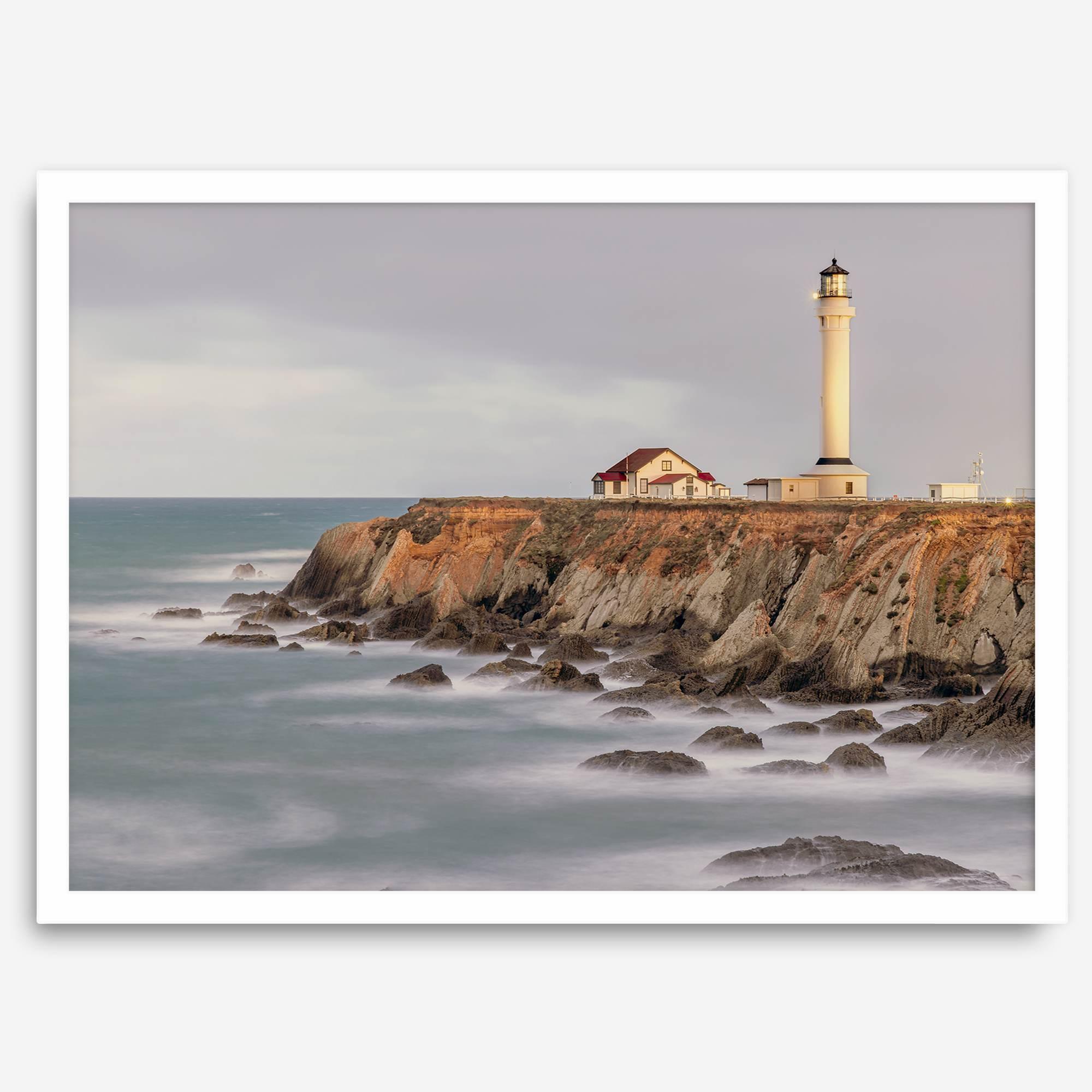 Long exposure fine art photography print of Pigeon Point Lighthouse at sunset. Golden light illuminates the lighthouse and cliffs, while the ocean surf crashes against the rocks in a creamy blur.