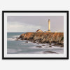 Long exposure fine art photography print of Pigeon Point Lighthouse at sunset. Golden light illuminates the lighthouse and cliffs, while the ocean surf crashes against the rocks in a creamy blur.