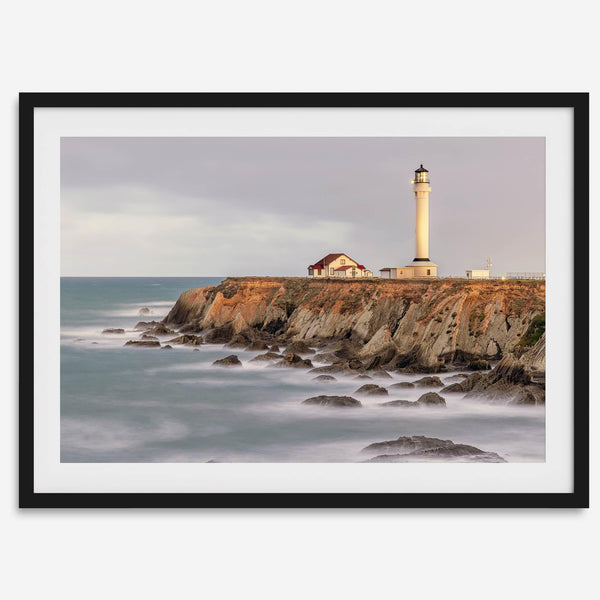 Long exposure fine art photography print of Pigeon Point Lighthouse at sunset. Golden light illuminates the lighthouse and cliffs, while the ocean surf crashes against the rocks in a creamy blur.