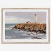 Long exposure fine art photography print of Pigeon Point Lighthouse at sunset. Golden light illuminates the lighthouse and cliffs, while the ocean surf crashes against the rocks in a creamy blur.