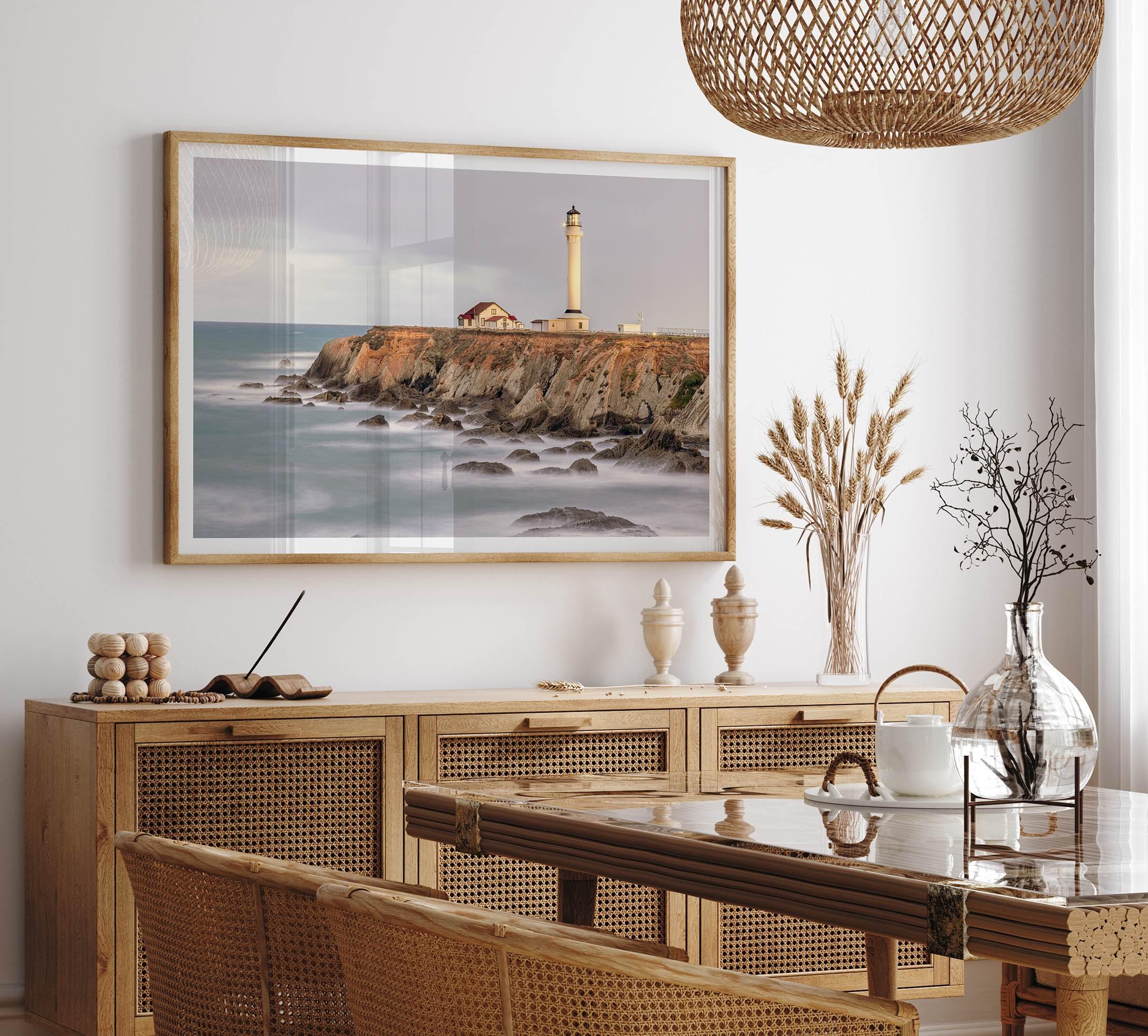 Long exposure fine art photography print of Pigeon Point Lighthouse at sunset. Golden light illuminates the lighthouse and cliffs, while the ocean surf crashes against the rocks in a creamy blur.