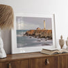 Long exposure fine art photography print of Pigeon Point Lighthouse at sunset. Golden light illuminates the lighthouse and cliffs, while the ocean surf crashes against the rocks in a creamy blur.