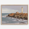 Long exposure fine art photography print of Pigeon Point Lighthouse at sunset. Golden light illuminates the lighthouse and cliffs, while the ocean surf crashes against the rocks in a creamy blur.