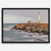 Long exposure fine art photography print of Pigeon Point Lighthouse at sunset. Golden light illuminates the lighthouse and cliffs, while the ocean surf crashes against the rocks in a creamy blur.