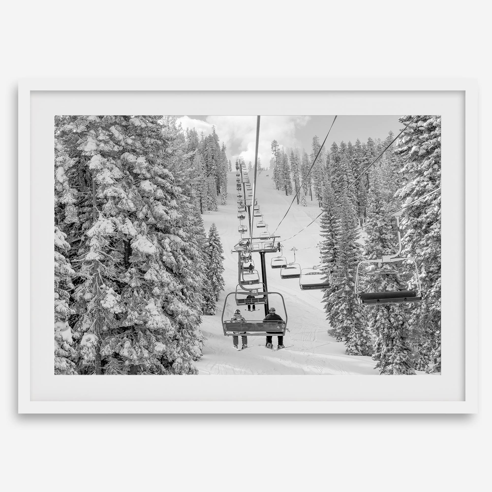 A fine art black and white mountain ski print showing a ski lift winding up the mountain with a stunning winter snow forest around it.