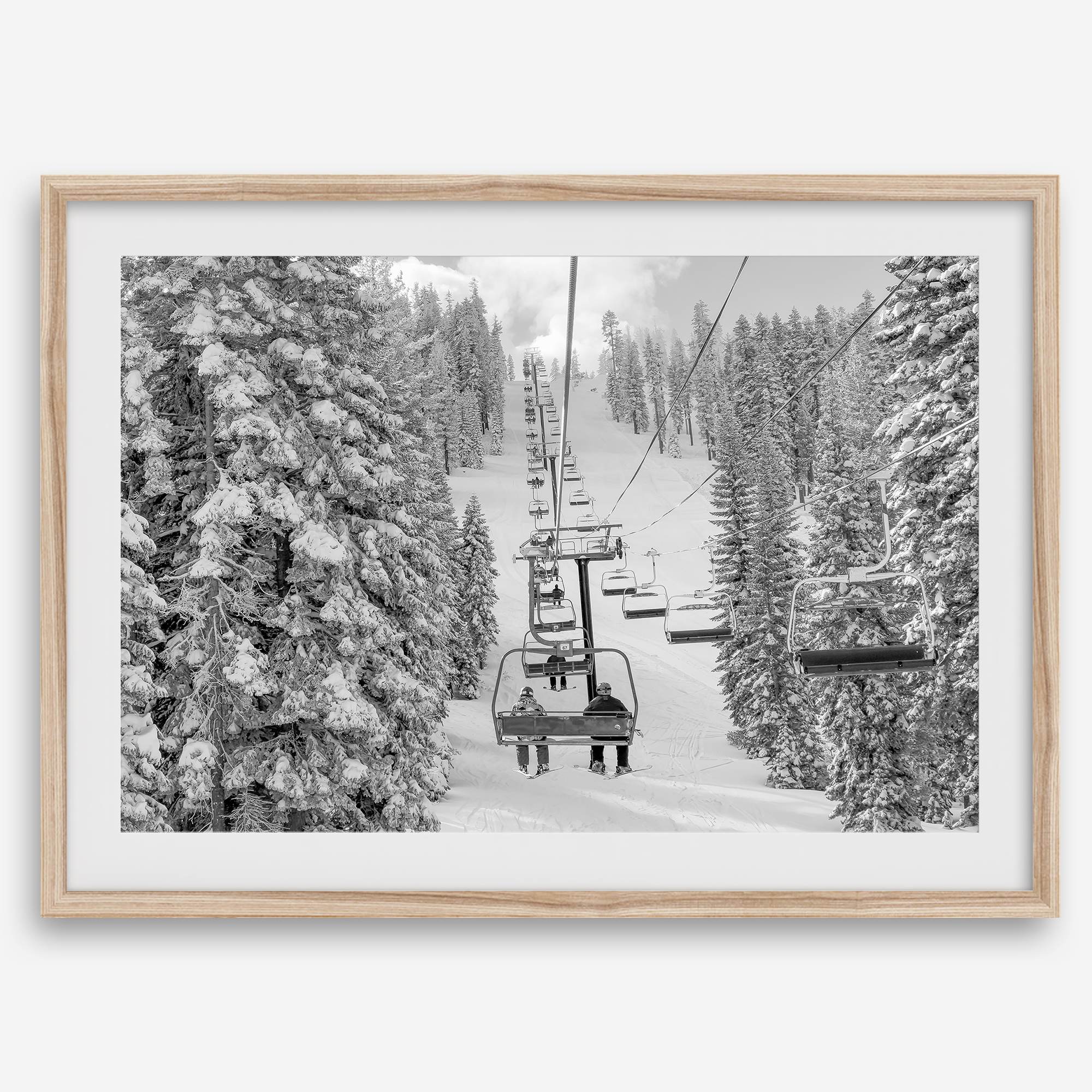 A fine art black and white mountain ski print showing a ski lift winding up the mountain with a stunning winter snow forest around it.