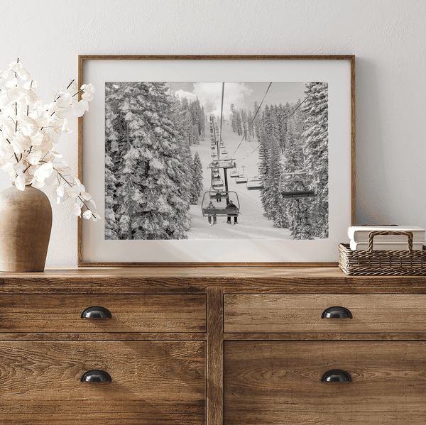 A fine art black and white mountain ski print showing a ski lift winding up the mountain with a stunning winter snow forest around it.