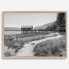 A fine art black and white vintage style framed photography print featuring a rustic old boathouse nested on a Lake Tahoe beach.