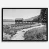 A fine art black and white vintage style framed photography print featuring a rustic old boathouse nested on a Lake Tahoe beach.