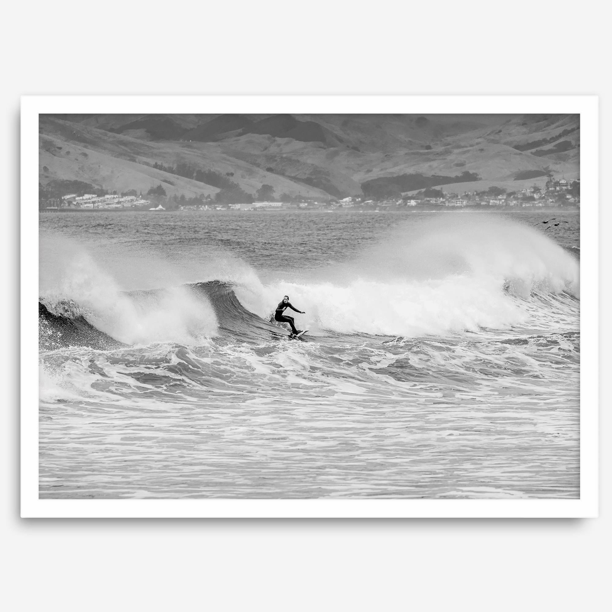 A black and white fine art surf print featuring a lone surfer riding the waves in Pismo Beach, California.