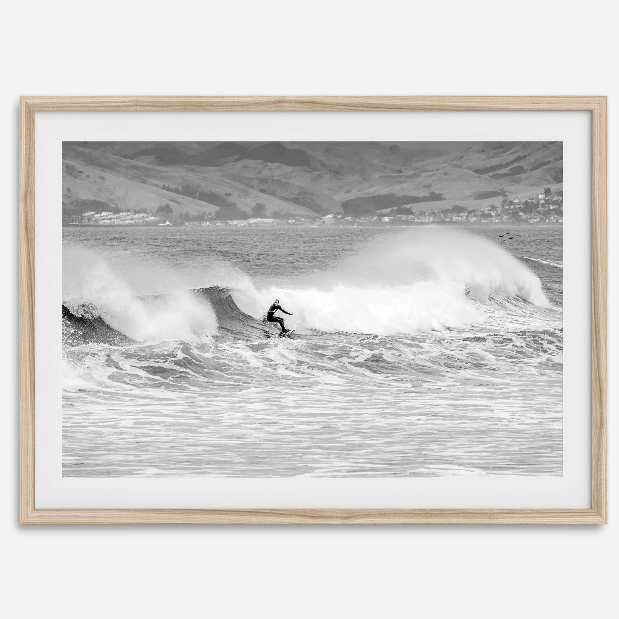 A black and white fine art surf print featuring a lone surfer riding the waves in Pismo Beach, California.