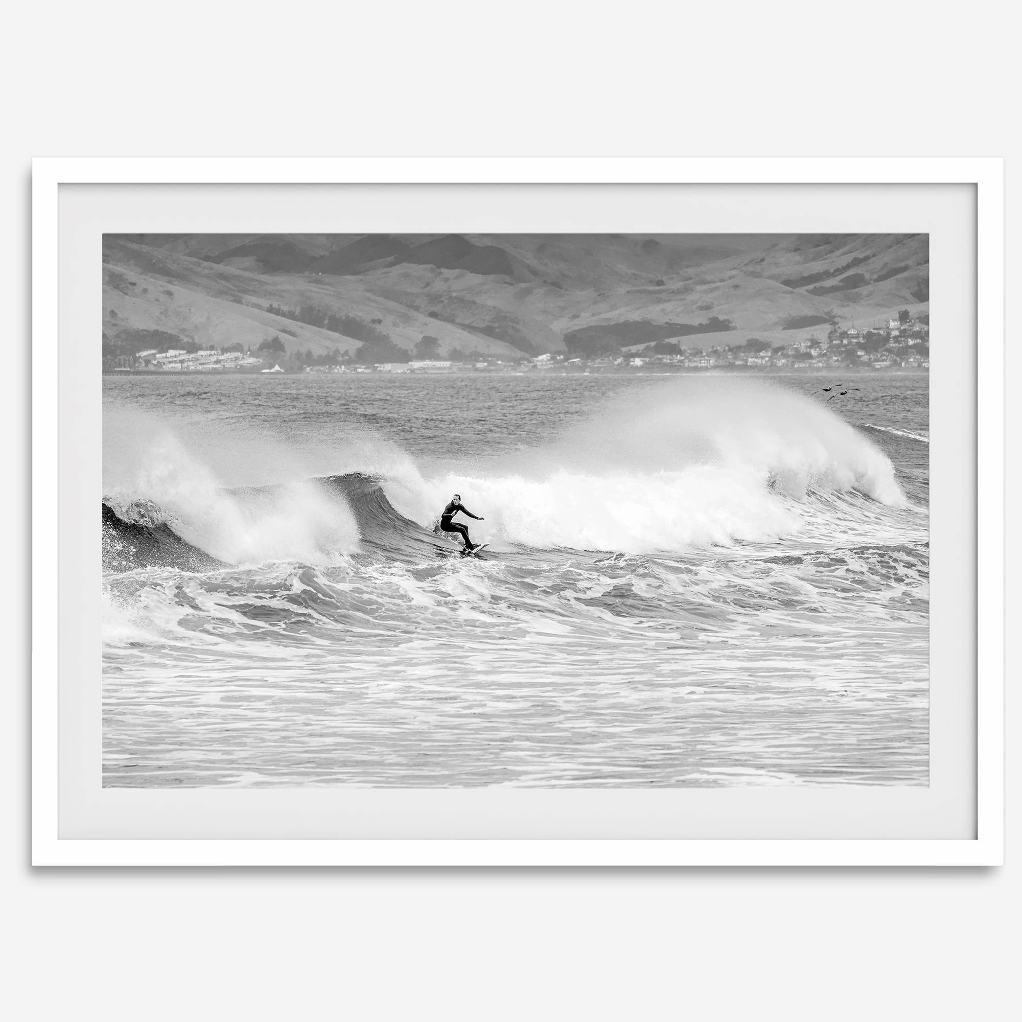 A black and white fine art surf print featuring a lone surfer riding the waves in Pismo Beach, California.