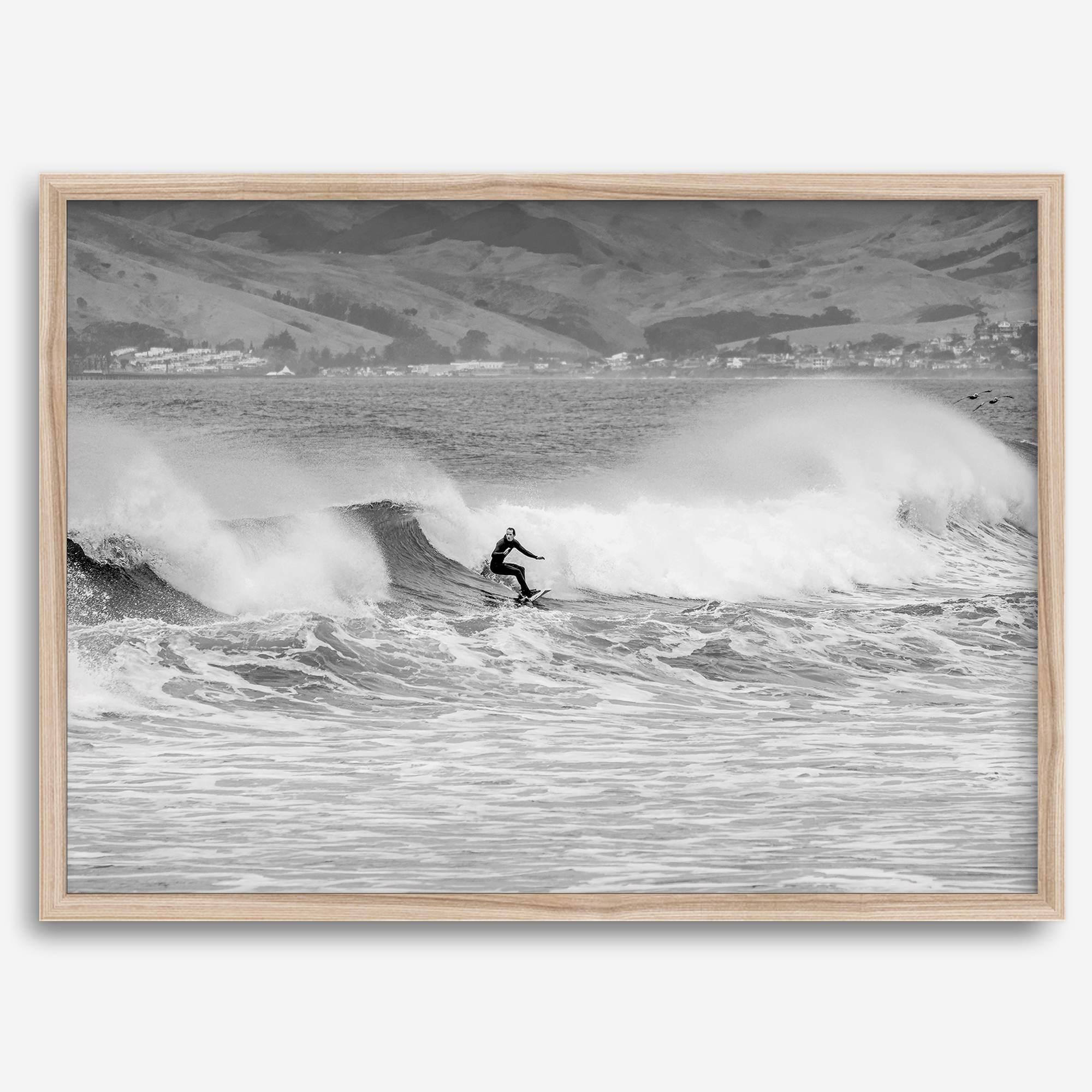 A black and white fine art surf print featuring a lone surfer riding the waves in Pismo Beach, California.